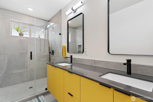 bathroom featuring double vanity, a shower stall, a sink, and recessed lighting