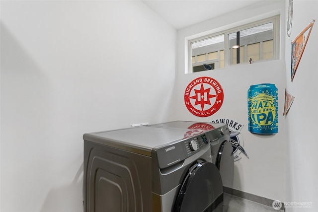 clothes washing area with laundry area, washing machine and dryer, and baseboards