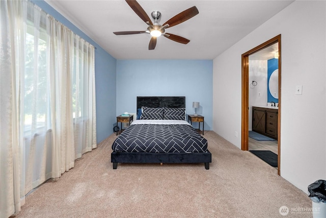 carpeted bedroom featuring multiple windows, a sink, a ceiling fan, and connected bathroom