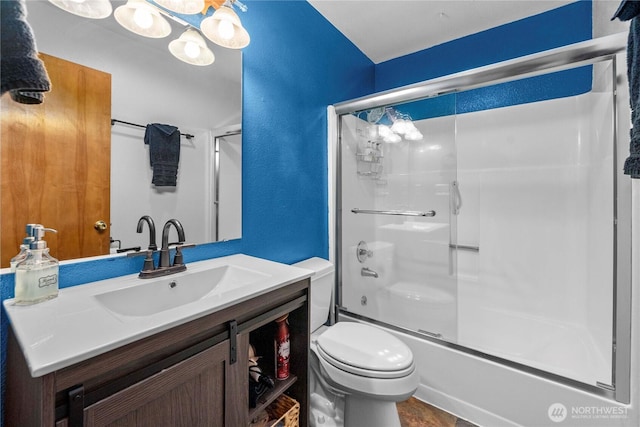 full bath featuring a textured wall, shower / bath combination with glass door, vanity, and toilet