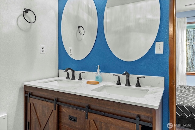 bathroom featuring a textured wall, a sink, and double vanity