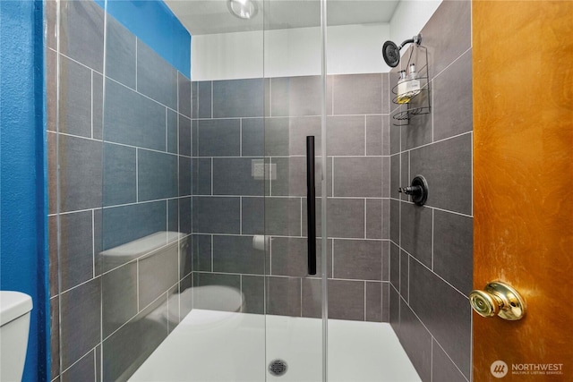 full bath featuring a stall shower and toilet