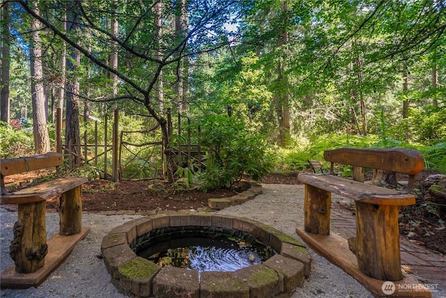 view of yard with an outdoor fire pit and a view of trees