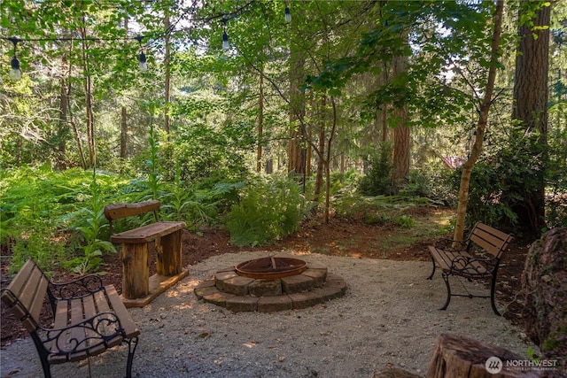 view of patio with an outdoor fire pit and a view of trees