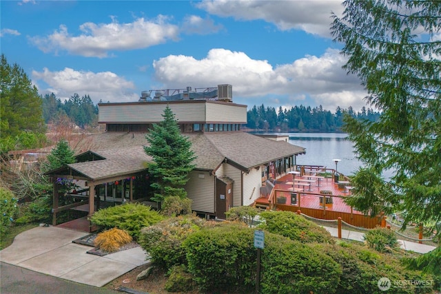 exterior space featuring a water view, a balcony, central AC unit, and roof with shingles