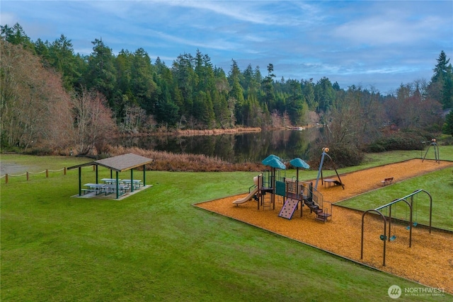 community playground featuring a forest view, a lawn, and a water view