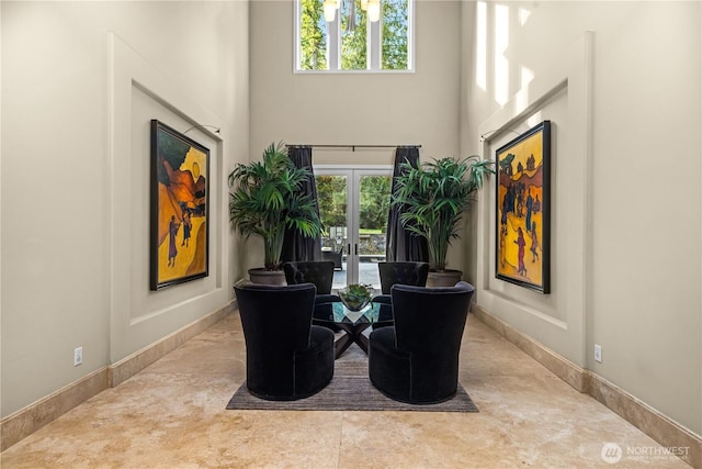 living area with a towering ceiling, baseboards, and french doors