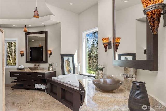 bathroom featuring a healthy amount of sunlight, a bathing tub, and a sink