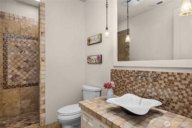 full bathroom with toilet, visible vents, a walk in shower, and vanity