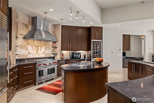 kitchen featuring wall chimney exhaust hood, an island with sink, modern cabinets, and high quality appliances