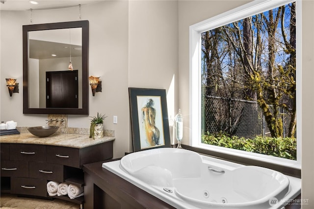 bathroom featuring a whirlpool tub, vanity, and a wealth of natural light