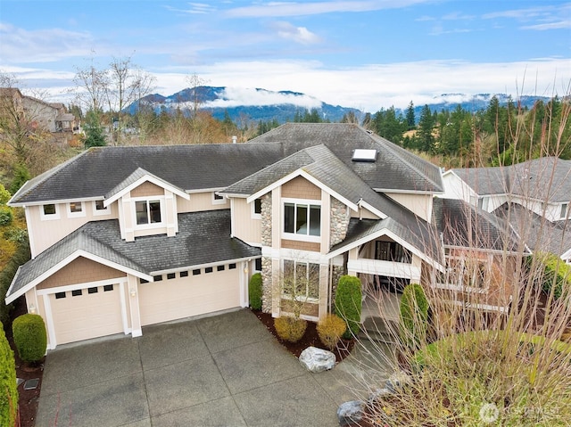 view of front of property with stone siding, a mountain view, concrete driveway, and a shingled roof