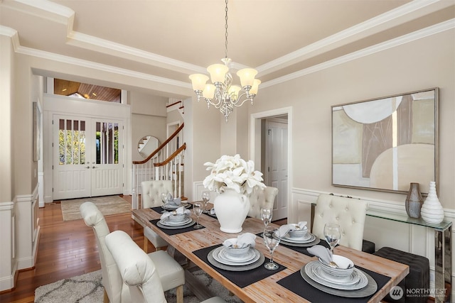 dining area with stairs, hardwood / wood-style flooring, ornamental molding, and a chandelier