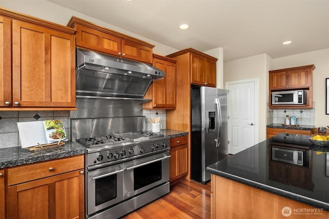 kitchen featuring brown cabinets, appliances with stainless steel finishes, and exhaust hood