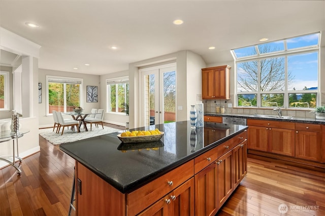 kitchen with a sink, backsplash, dark wood-style floors, and a center island