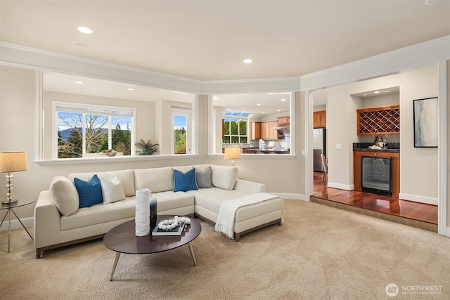 living room featuring a wealth of natural light, light colored carpet, wine cooler, and a bar