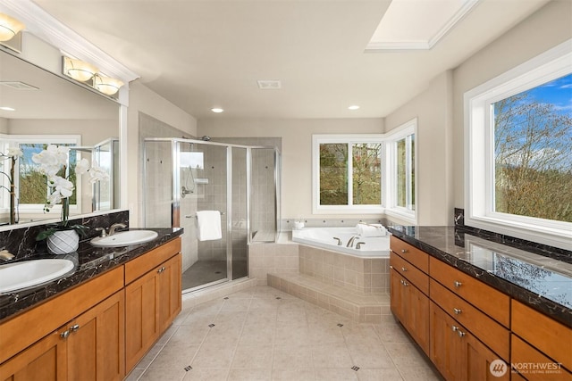 full bathroom featuring tile patterned floors, a skylight, a bath, and a sink