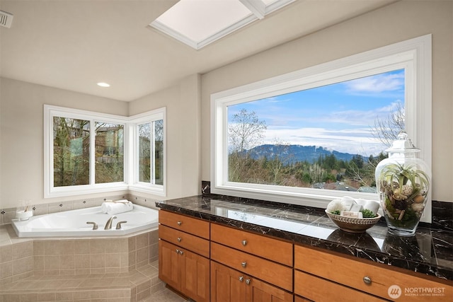 full bath with a wealth of natural light, a mountain view, a garden tub, and visible vents