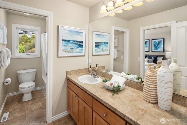 bathroom with vanity, toilet, baseboards, and visible vents