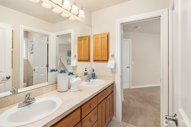 full bathroom with double vanity, toilet, baseboards, and a sink