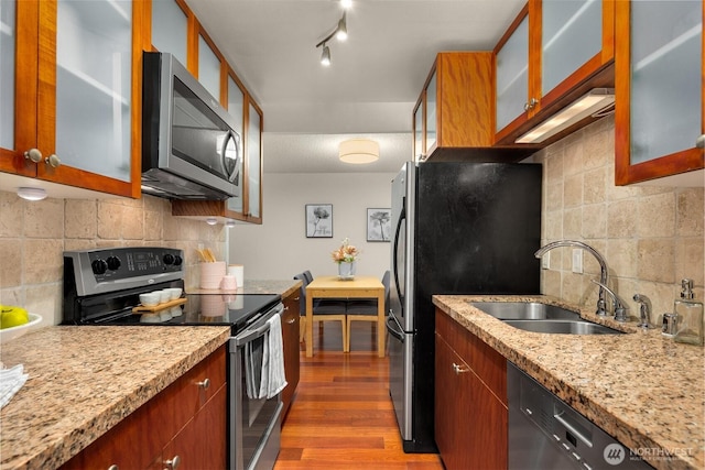 kitchen with dark wood-style floors, stainless steel appliances, decorative backsplash, glass insert cabinets, and a sink