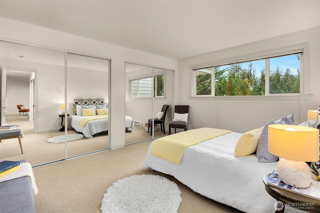 carpeted bedroom with a textured ceiling and multiple closets