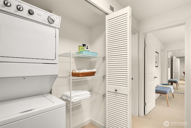 washroom featuring laundry area, stacked washer / drying machine, and light colored carpet