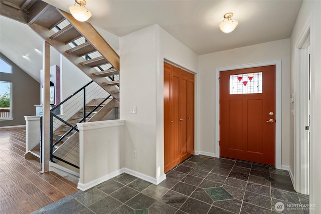 foyer entrance featuring stairway and baseboards