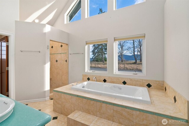 bathroom with tiled shower, a high ceiling, tile patterned flooring, and a bath