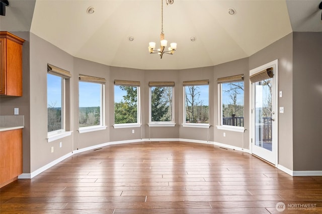 unfurnished dining area with lofted ceiling, dark wood-style floors, and baseboards