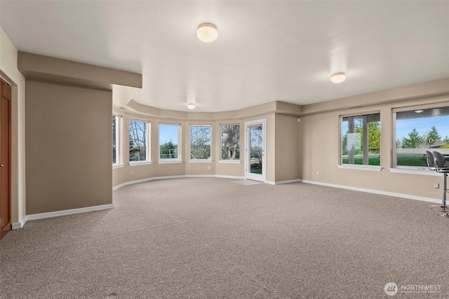 unfurnished living room with carpet floors, plenty of natural light, and baseboards