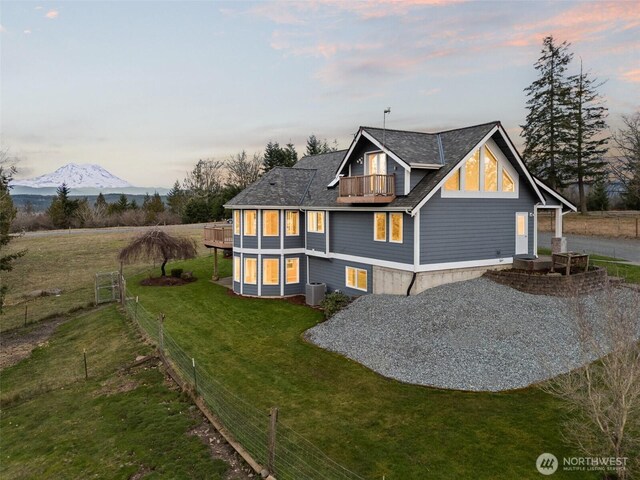 exterior space featuring a balcony, fence, a mountain view, central AC, and a front yard