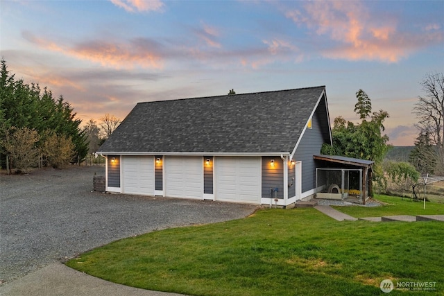 exterior space with a yard, roof with shingles, driveway, and a garage