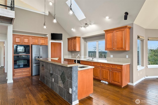 kitchen with black appliances, a sink, dark wood finished floors, and brown cabinets