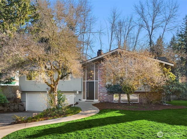 split foyer home with a garage, a chimney, a front lawn, and concrete driveway