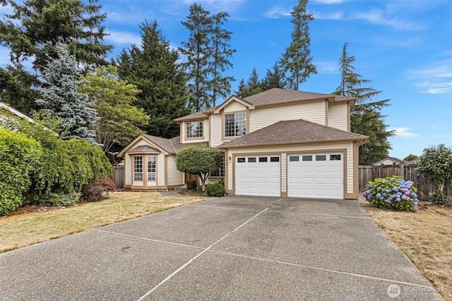 traditional-style house featuring a garage, fence, concrete driveway, and roof with shingles