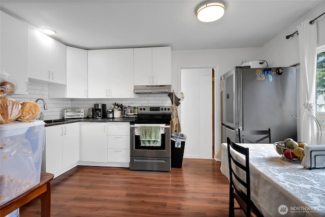 kitchen with under cabinet range hood, stainless steel appliances, a sink, tasteful backsplash, and dark wood finished floors