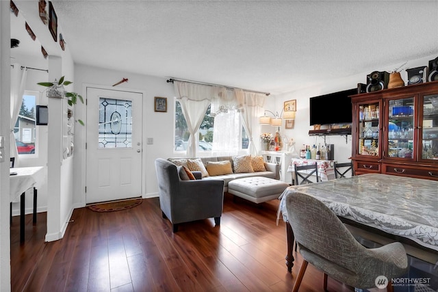 living area featuring dark wood-style floors, a textured ceiling, and baseboards