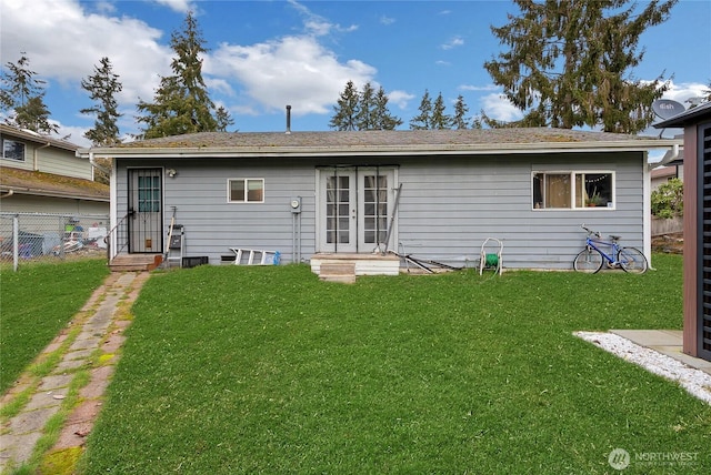 back of property featuring fence, a lawn, and french doors