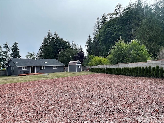 view of yard featuring a storage shed, an outdoor structure, and fence