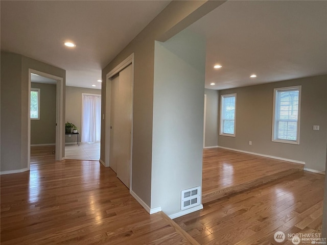 hallway with baseboards, wood finished floors, visible vents, and recessed lighting