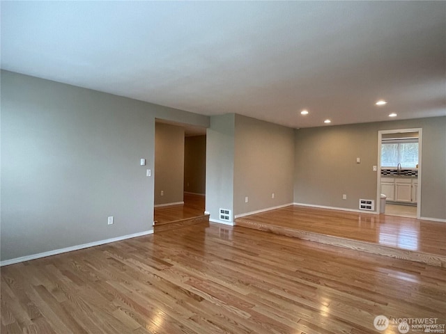 unfurnished room with baseboards, light wood finished floors, visible vents, and recessed lighting