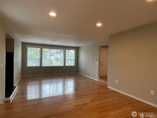 spare room featuring recessed lighting, wood finished floors, and baseboards