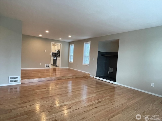 unfurnished living room featuring a tile fireplace, light wood-style flooring, and recessed lighting