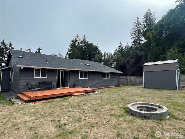 back of property with a fire pit, a lawn, a gate, fence, and a deck