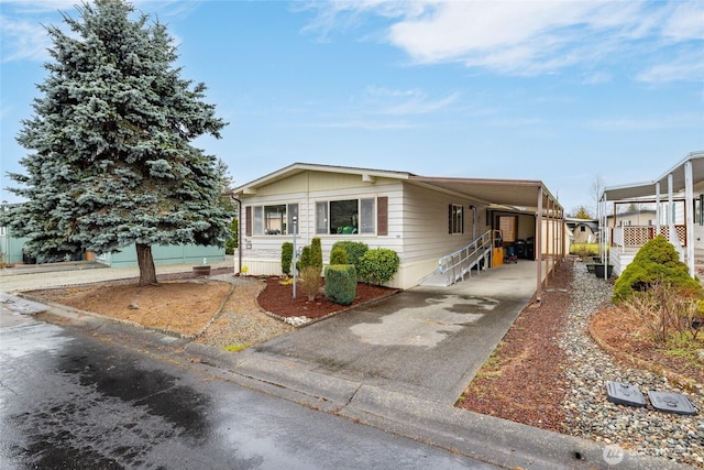 manufactured / mobile home featuring an attached carport and concrete driveway