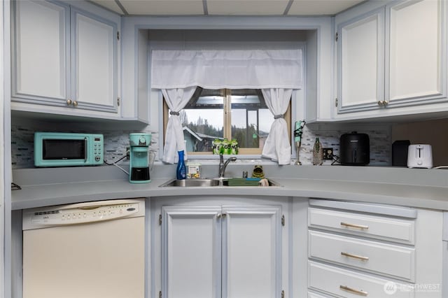 kitchen featuring light countertops, decorative backsplash, white cabinets, a sink, and white appliances