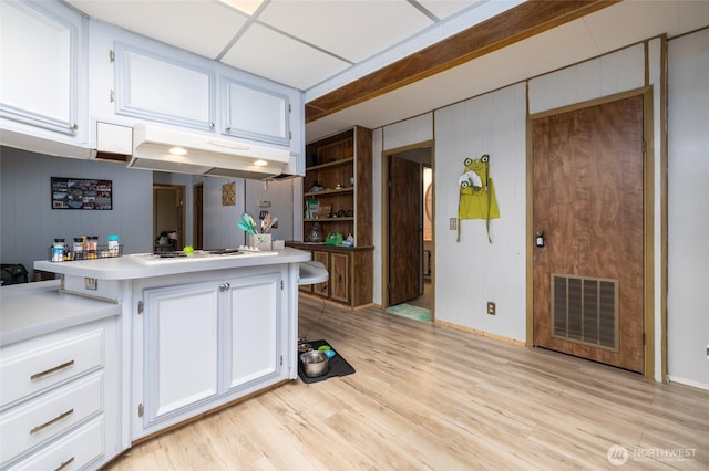 kitchen featuring white cooktop, light countertops, visible vents, and under cabinet range hood