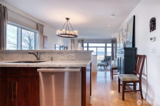 kitchen with light wood-style flooring, open floor plan, light stone countertops, stainless steel dishwasher, and a sink