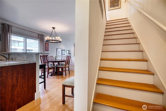 stairs with an inviting chandelier and hardwood / wood-style floors